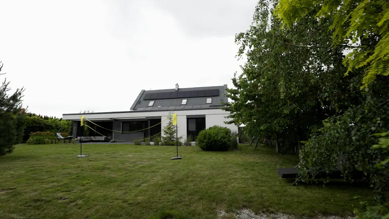 Drewniana pergola z zielenią i miejscem wypoczynkowym w ogrodzie