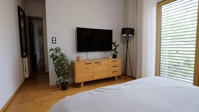 Sypialnia z podwójnym łóżkiem, telewizorem i dużym oknem